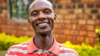 Habitat homeowner in Kenya facing the camera and smiling while standing in front of his home.