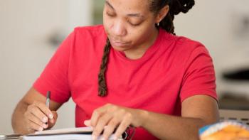 Habitat for Humanity applicant for the affordable homeownership program sits in a red shirt at a desk filling out paperwork.