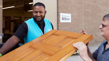 ReStore staff member helping man carry a donated door.