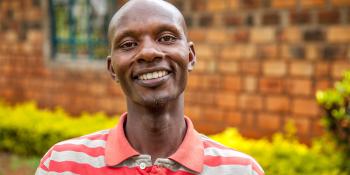 Habitat homeowner in Kenya facing the camera and smiling while standing in front of his home.