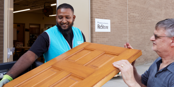 ReStore staff member helping man carry a donated door.